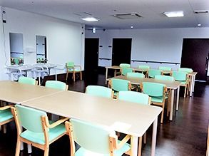 四人掛け・六人掛けのテーブルと椅子が並んでいる施設内の共有スペースの様子