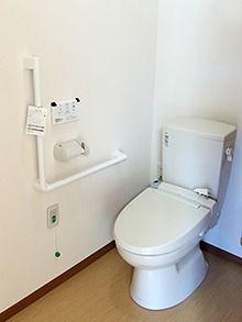 高齢者施設に取り付けられているトイレの写真。右側に手すりと緊急コールが付いている様子
