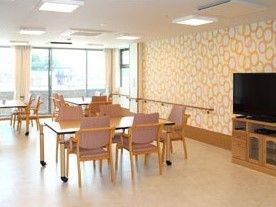 日当たりのよい食堂には複数のダイニングテーブルと大型テレビが置かれ、カラフルな壁紙が貼られている。