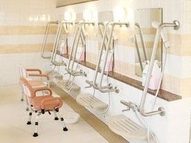 手すり付きのシャワーにはそれぞれ鏡が付き、シャンプーなども設置され、シャワーチェアも置かれている。