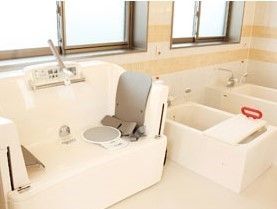 バスボードが設置された個浴と機械浴が並んで設置された明るい浴室。