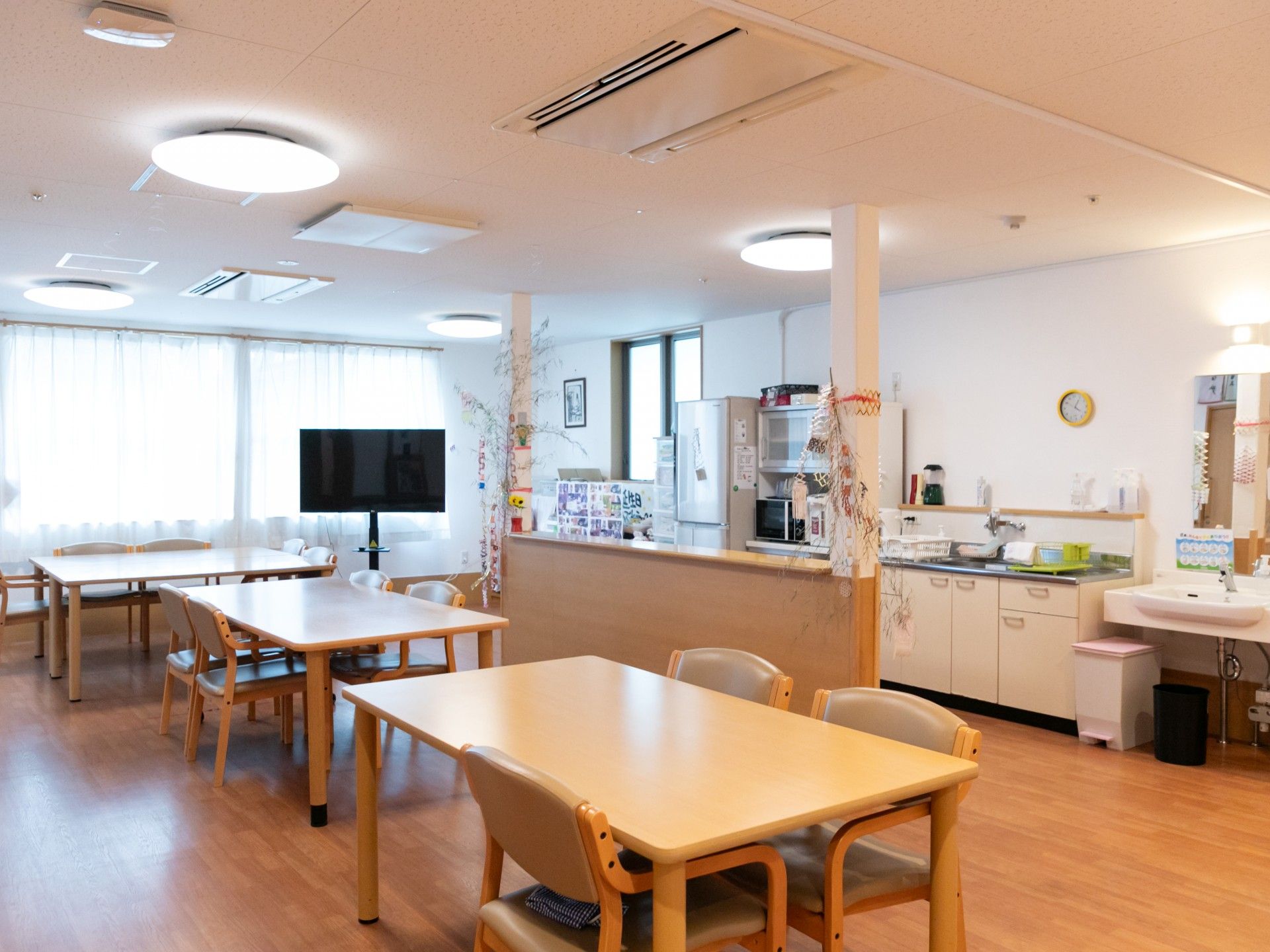 エアコンが設置された居室にはタンスや応接セット、ベッドが置かれている。季節の花も飾られ温かい雰囲気。