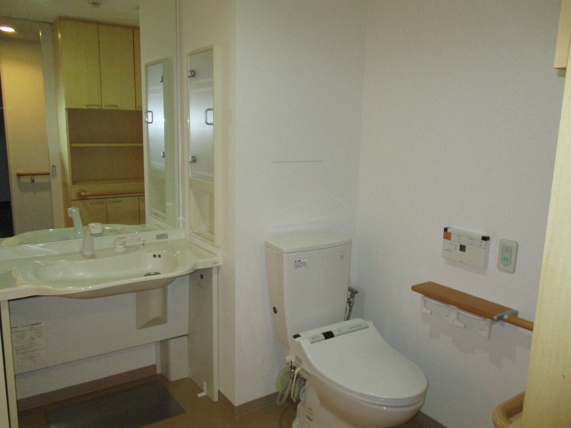 洗面台がすぐ横についたトイレの様子。ウォシュレットと緊急コールがついているトイレ