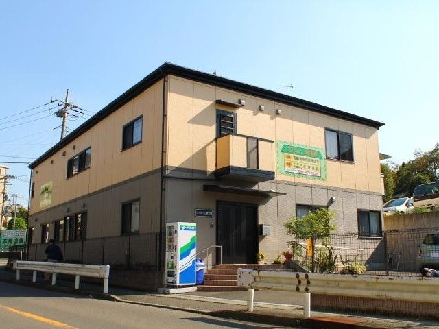 ２階建てのブラウン系の建物がある敷地内には季節の木が植えられ、アットホームな雰囲気。