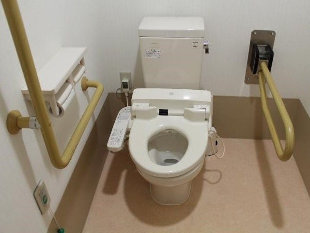 可動式の手すりが付いたトイレには壁にも手すりが設置され、押しボタン式の呼び出しコールも設置されている。