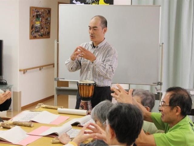 男性講師が前で指導している音楽療法の一コマ。スタッフも入居者と一緒に行っている。