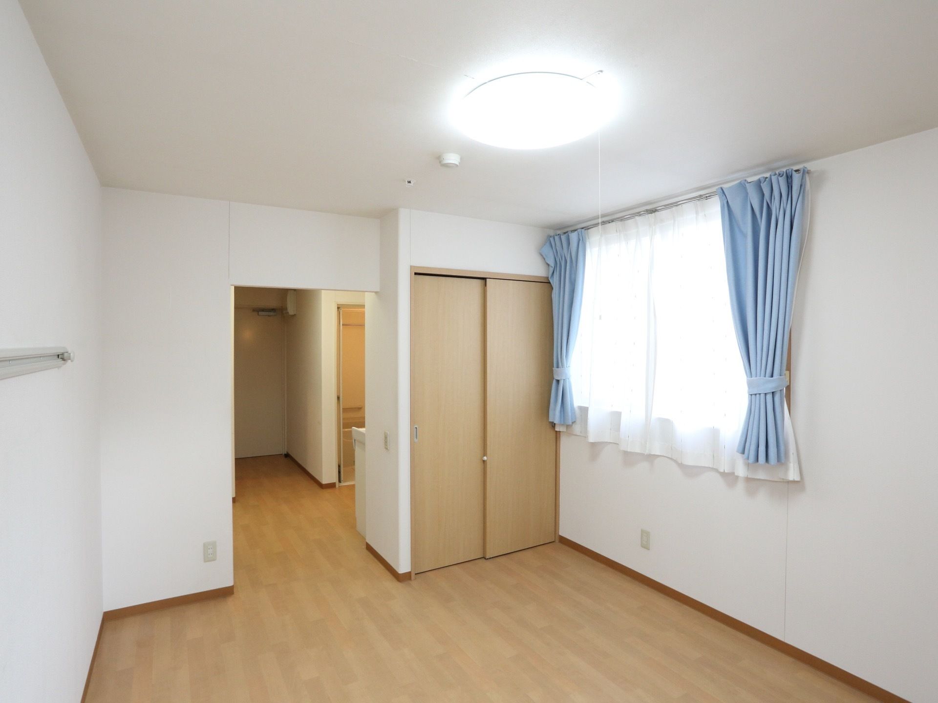 居室の居住スペースには収納があり、その横に窓が開いている。入口から入ると左手にトイレと洗面台がある。