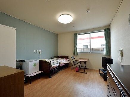 日当たりのいい場所でカルテを見ながら真剣な表情で話している女性スタッフと高齢女性。
