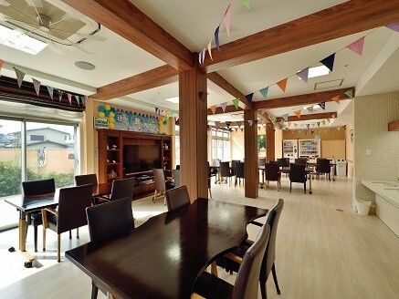 日当たりのいい屋外で男性スタッフに押してもらいながら前進している車いすの高齢女性。