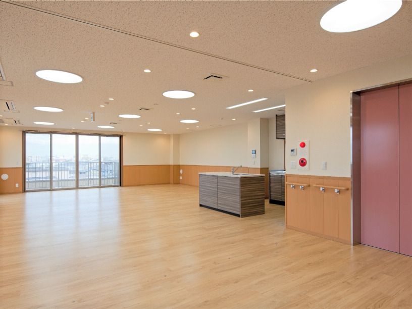 ピンクのエレベーターが設置された館内には広い共有スペースがあり、家具は置かれていないがキッチンがある。大きな窓があり、カーテンはない。