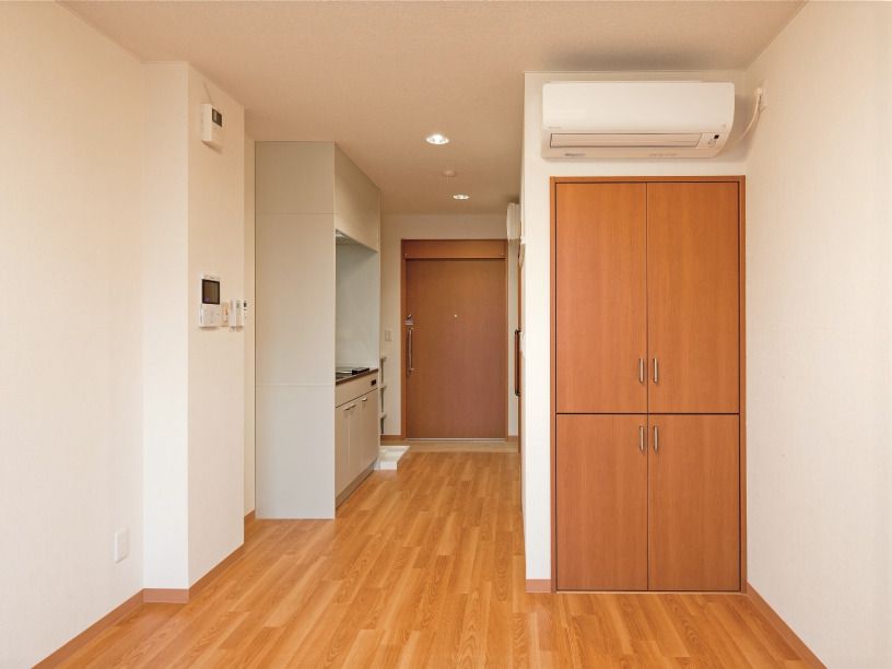 クローゼットやエアコンが付いたフローリングの部屋。オール電化のキッチンもあり、インターフォンのモニターが壁に設置されている。