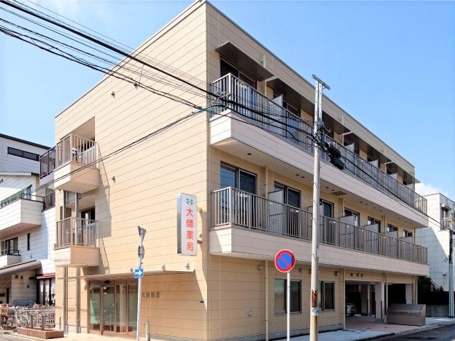 ベランダや非常用階段、レスキューベランダが付いた安全性の高い3階建ての建物。日当たりがよく、周りにもたくさんの建物が建っている。
