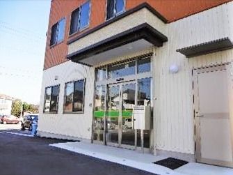1階部分は白、2階部分はブラウンの外壁。玄関には屋根が付いている。