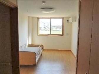 居室内にはエアコンとベッドがあり、手前にはトイレと収納がある。