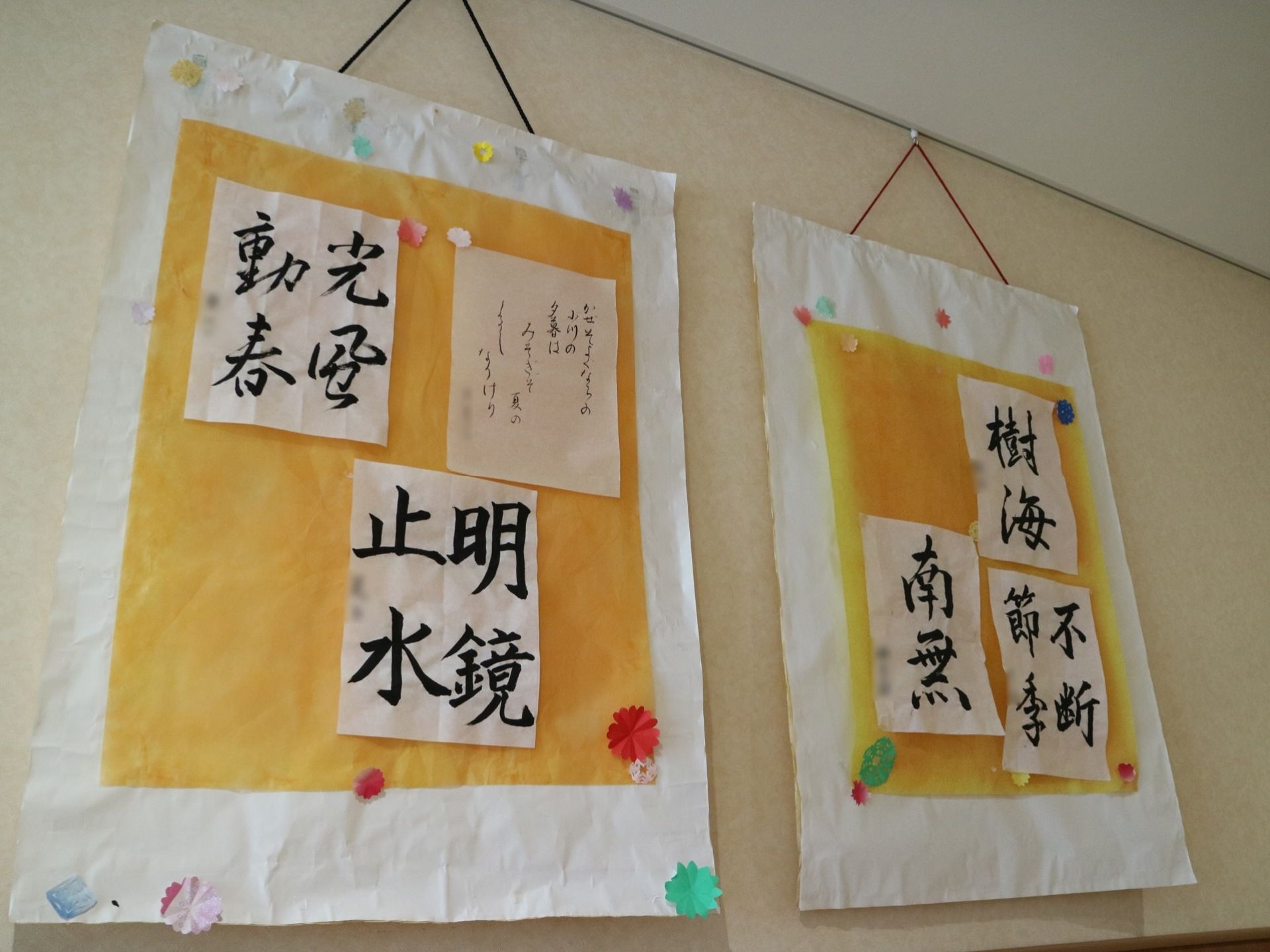 入居者様が書いた書道の作品が、模造紙に貼られて飾られている。室内は、白を基調とした清潔感のある壁紙となっている。