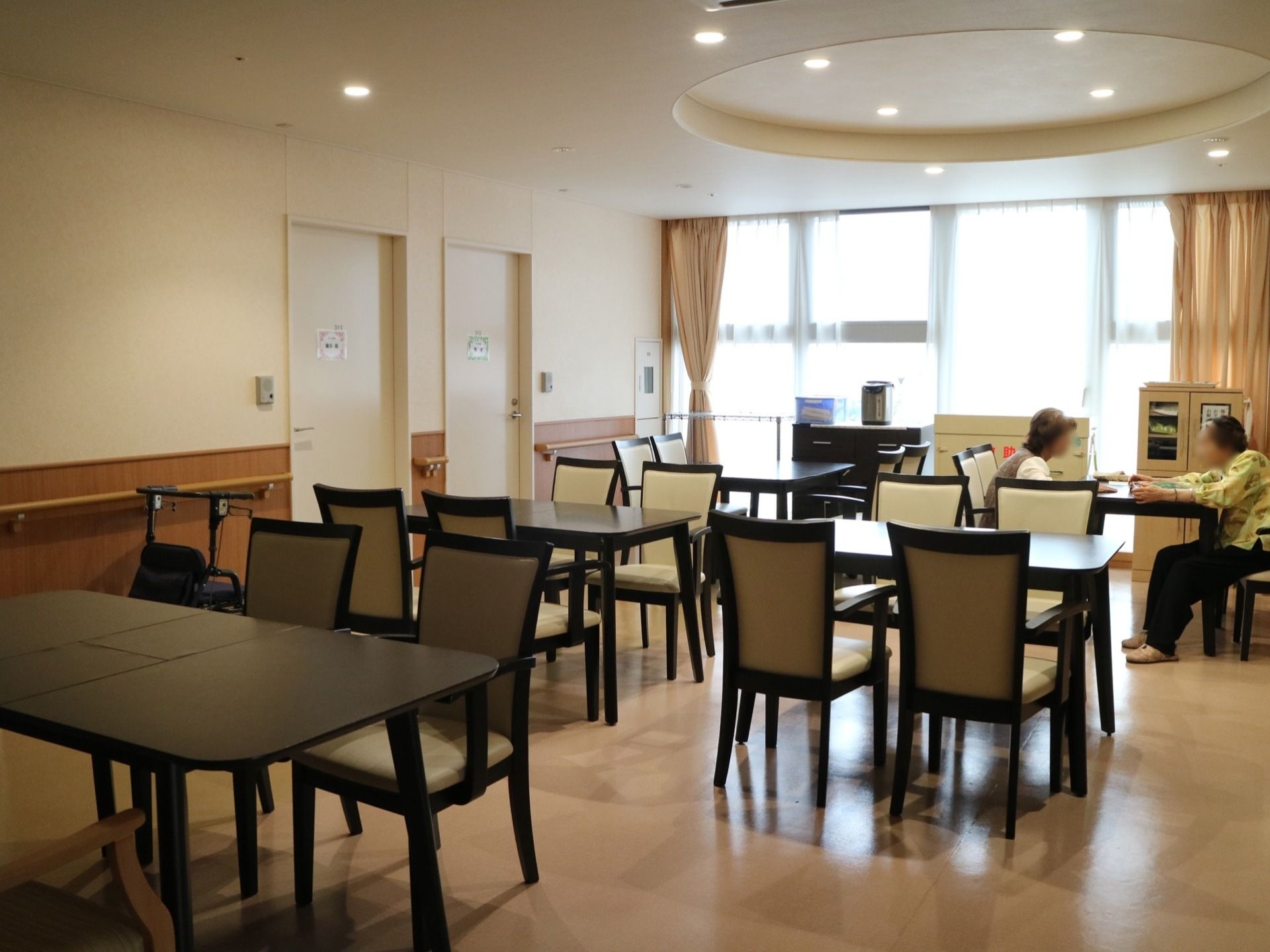 居室前に設けられている、開放的な食堂である。４人掛けのテーブルとひじ掛け付きの椅子が、複数組セッティングされている。