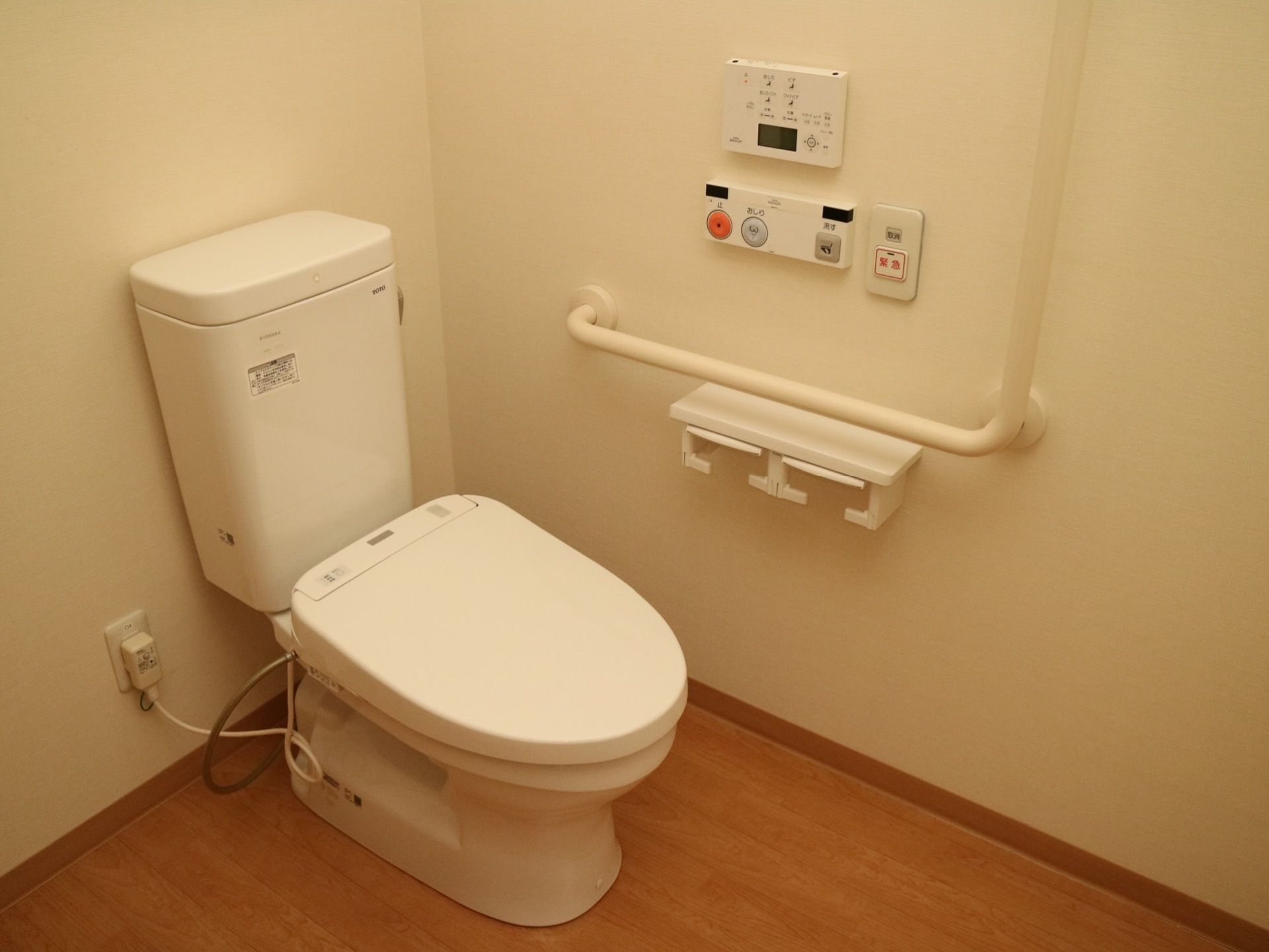 トイレは温水洗浄機能付きとなっており、壁には操作パネルやＬ字型の手すり、呼び出しボタンが設置されている。