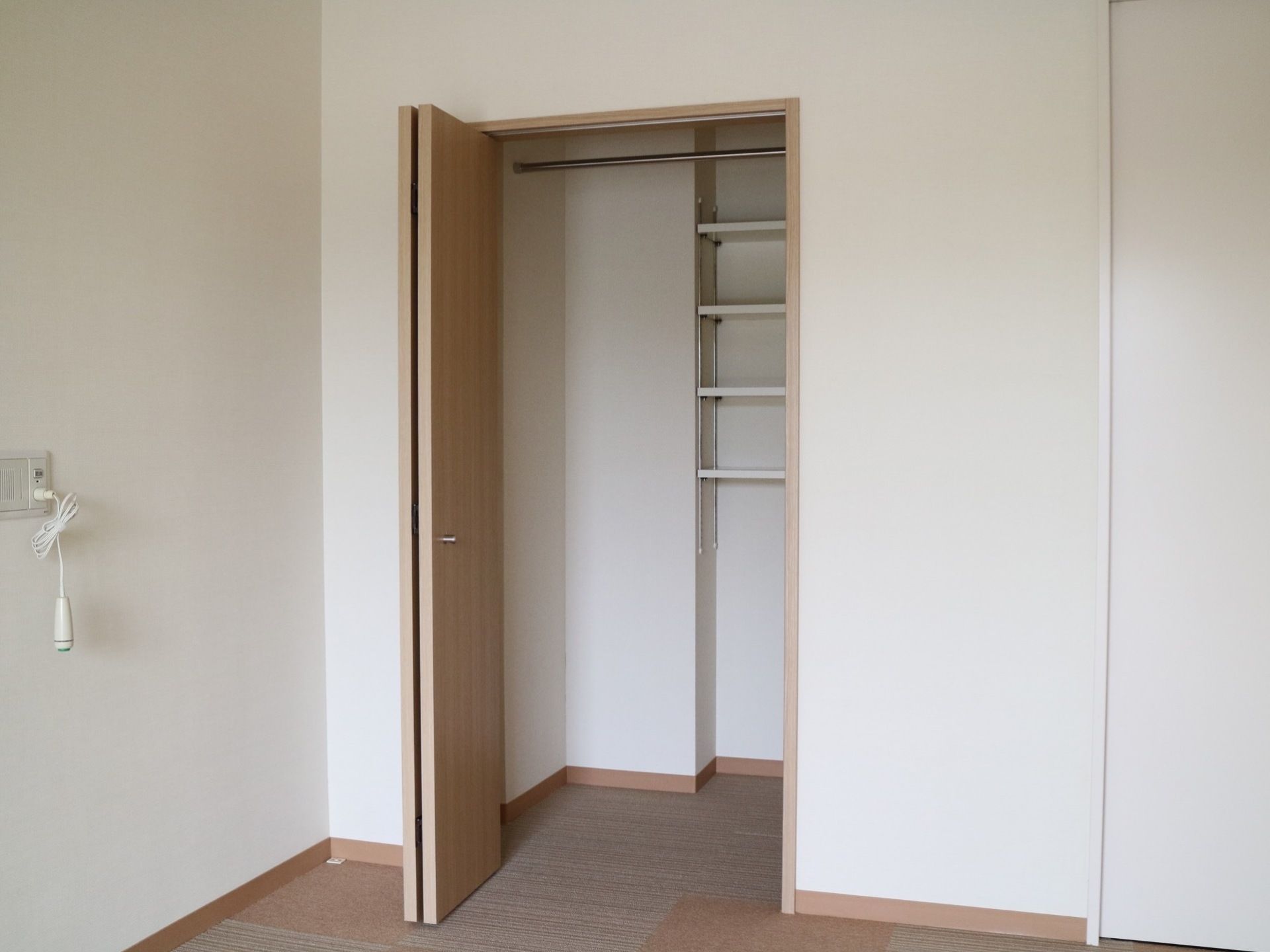 居室に横開きの大容量のクローゼットが設置されており、内部には棚やハンガーポールが取り付けられている。