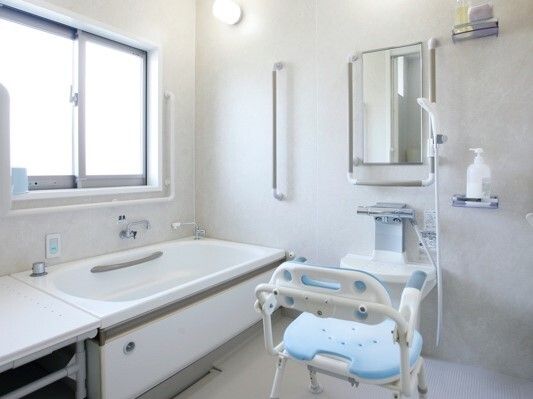 手すりが多く付いた一人用のお風呂にはシャワーやシャワーチェアがあり、浴槽の横にはベンチもある。