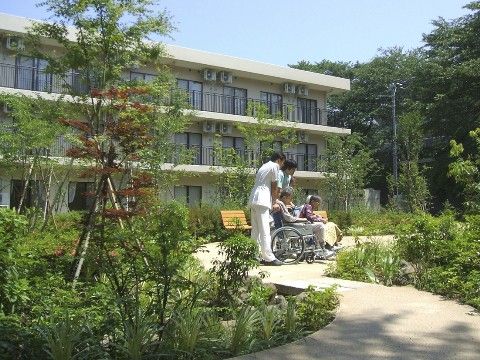 3階建ての白い建物と緑豊かな庭