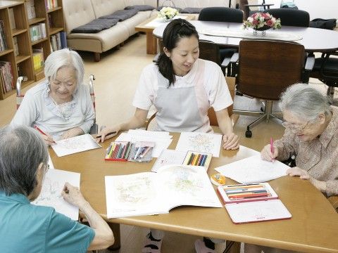テーブルを囲んで塗り絵をする高齢者
