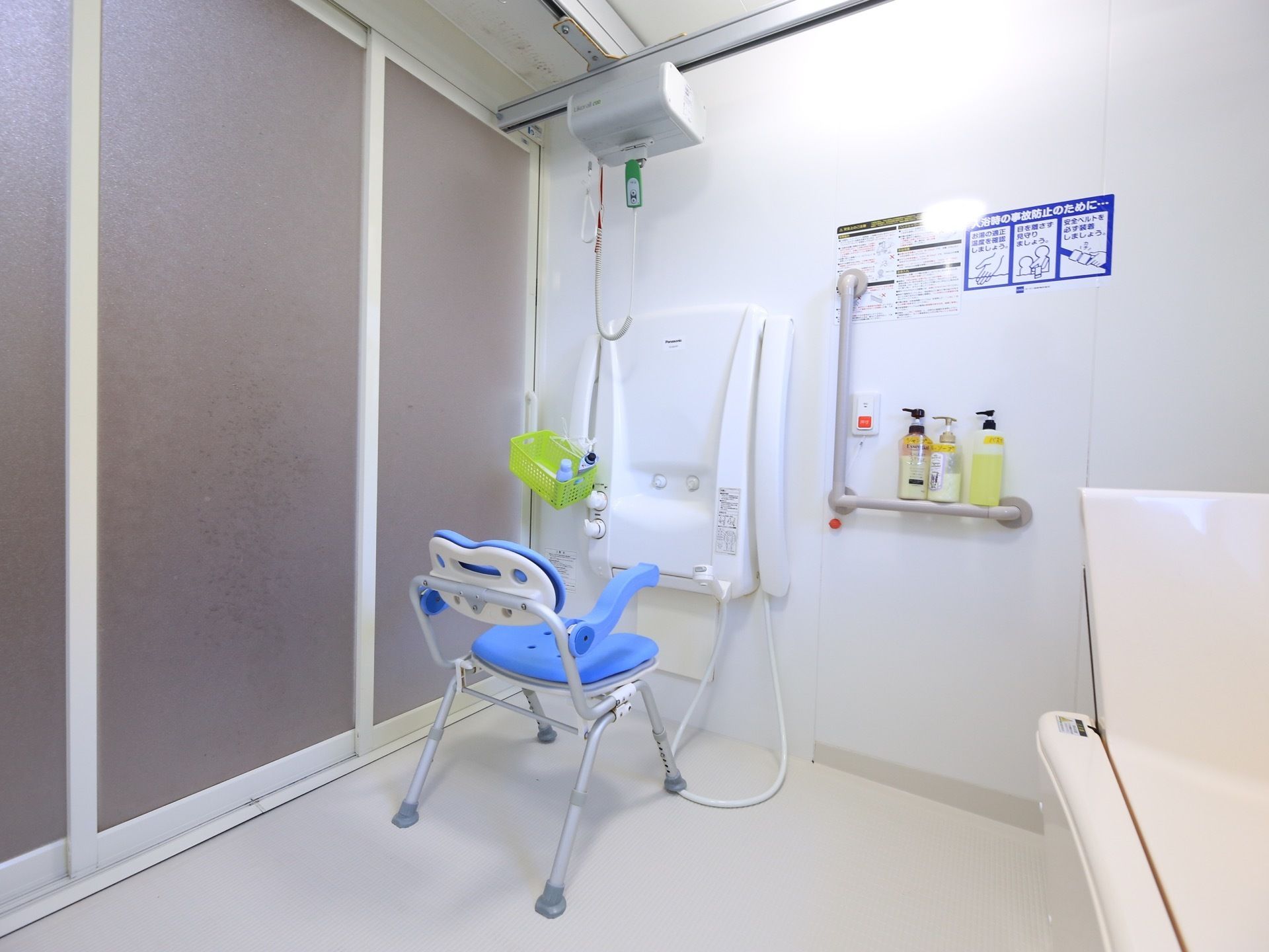 白を基調とした浴室で、清潔感がある。手すりや背もたれ付きの椅子が用意されており、安心して利用することができる。