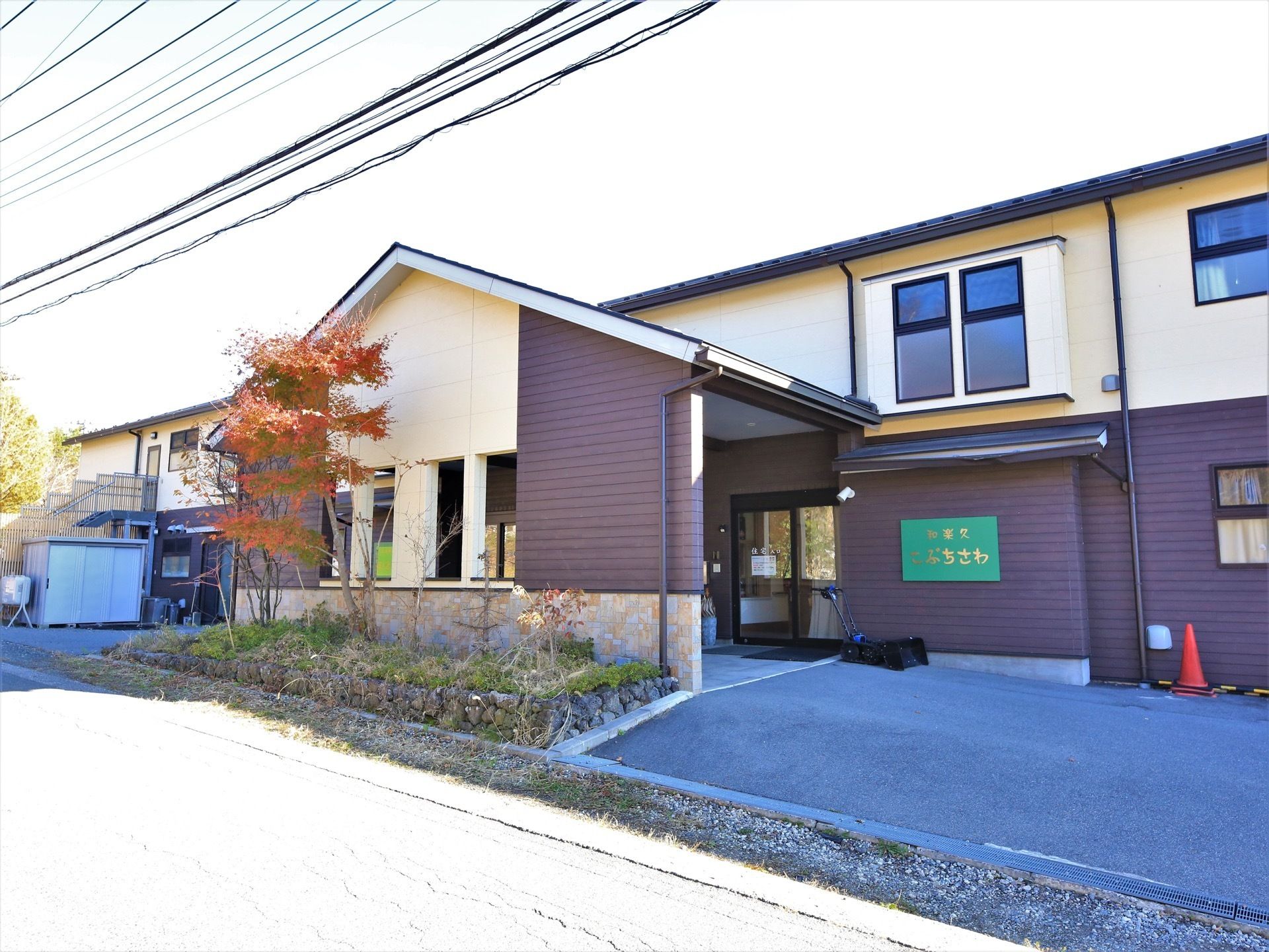 外壁にベージュ色とブラウン色の２色が使われた２階建ての建物である。玄関前のスペースは広く、大きな屋根が設置されている。