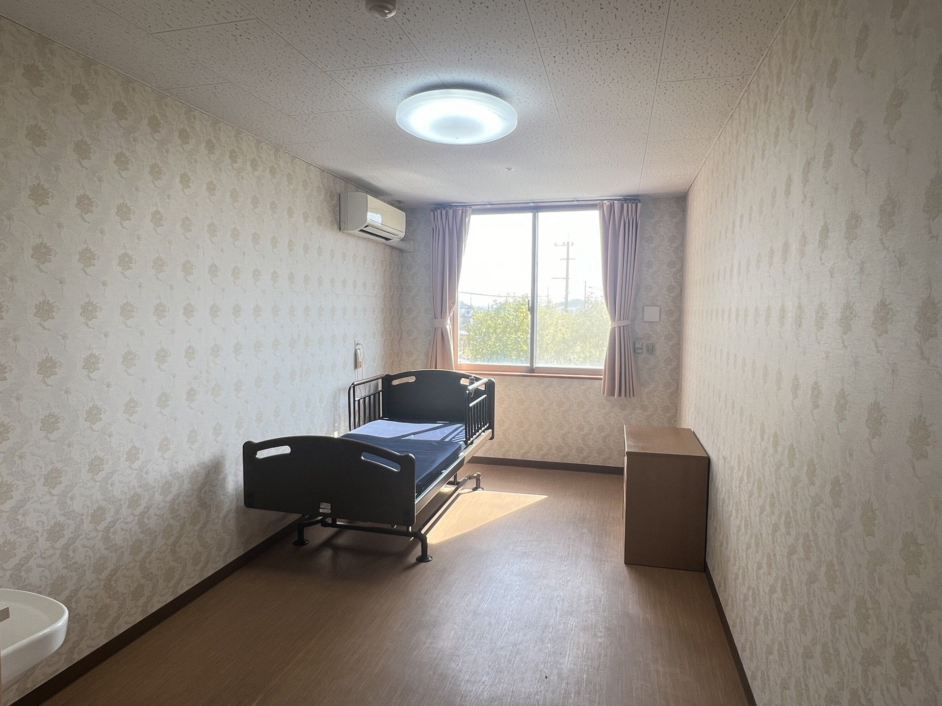 ブルーのユニフォームを着た男性スタッフと高齢女性が笑顔で体操をしている。2人は並んで立っている。