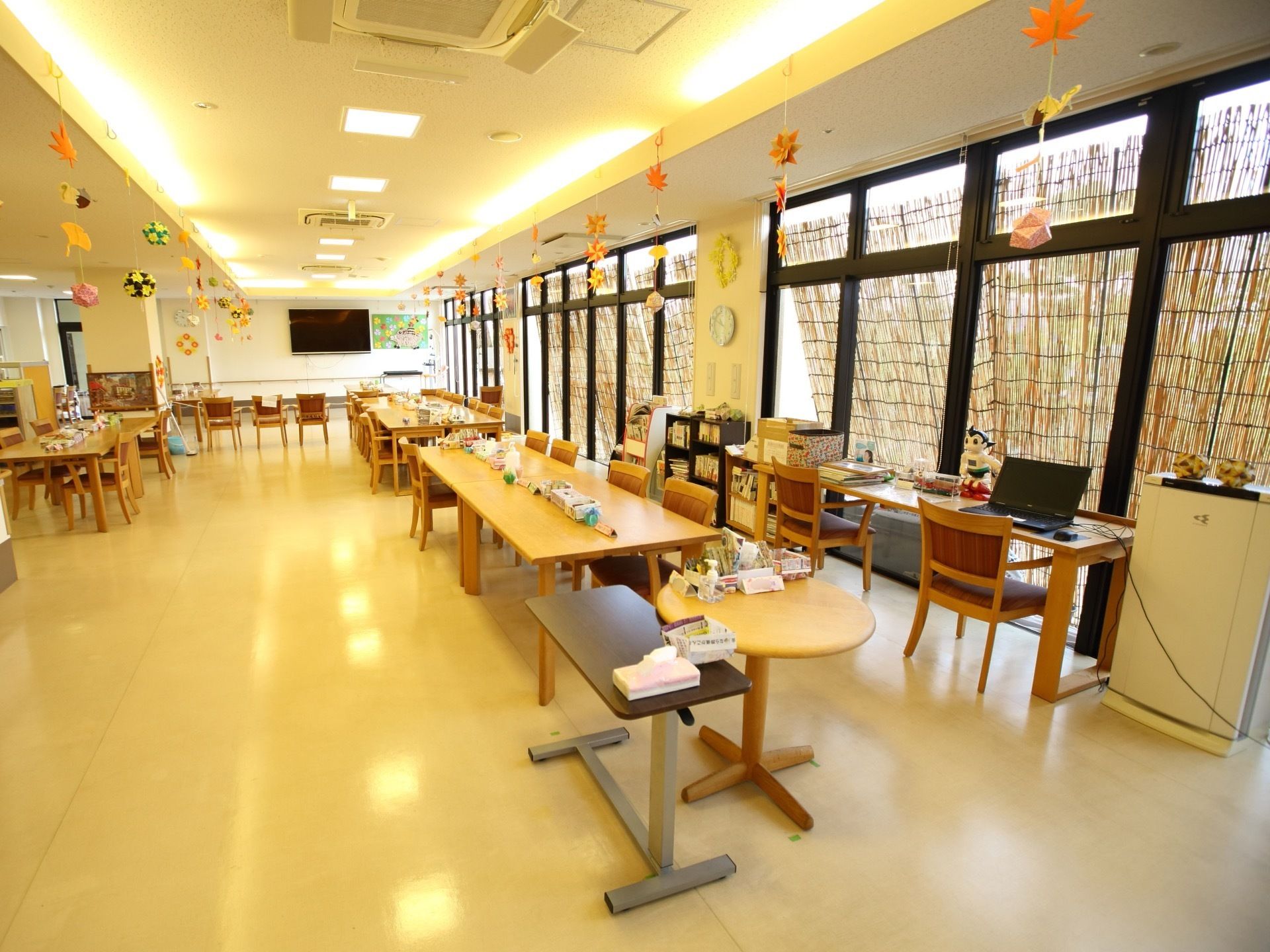 窓が複数ある部屋では、入居者様が並んだり向き合ったりして座る。パソコンや冷蔵庫が置かれており、共用している。