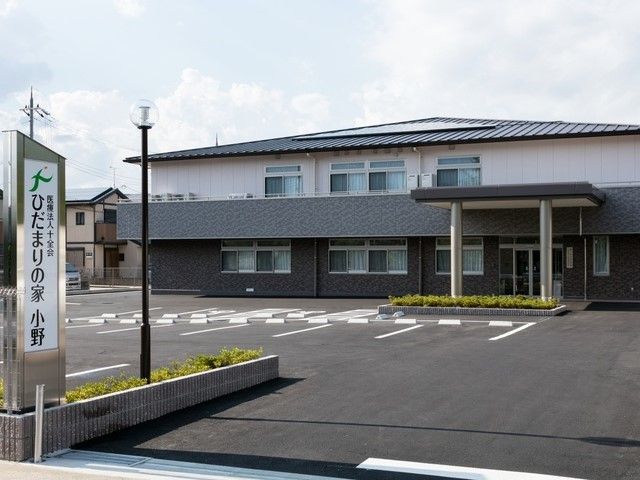 広い駐車場も完備。２階建ての建物は白とグレーで落ち着いた雰囲気。