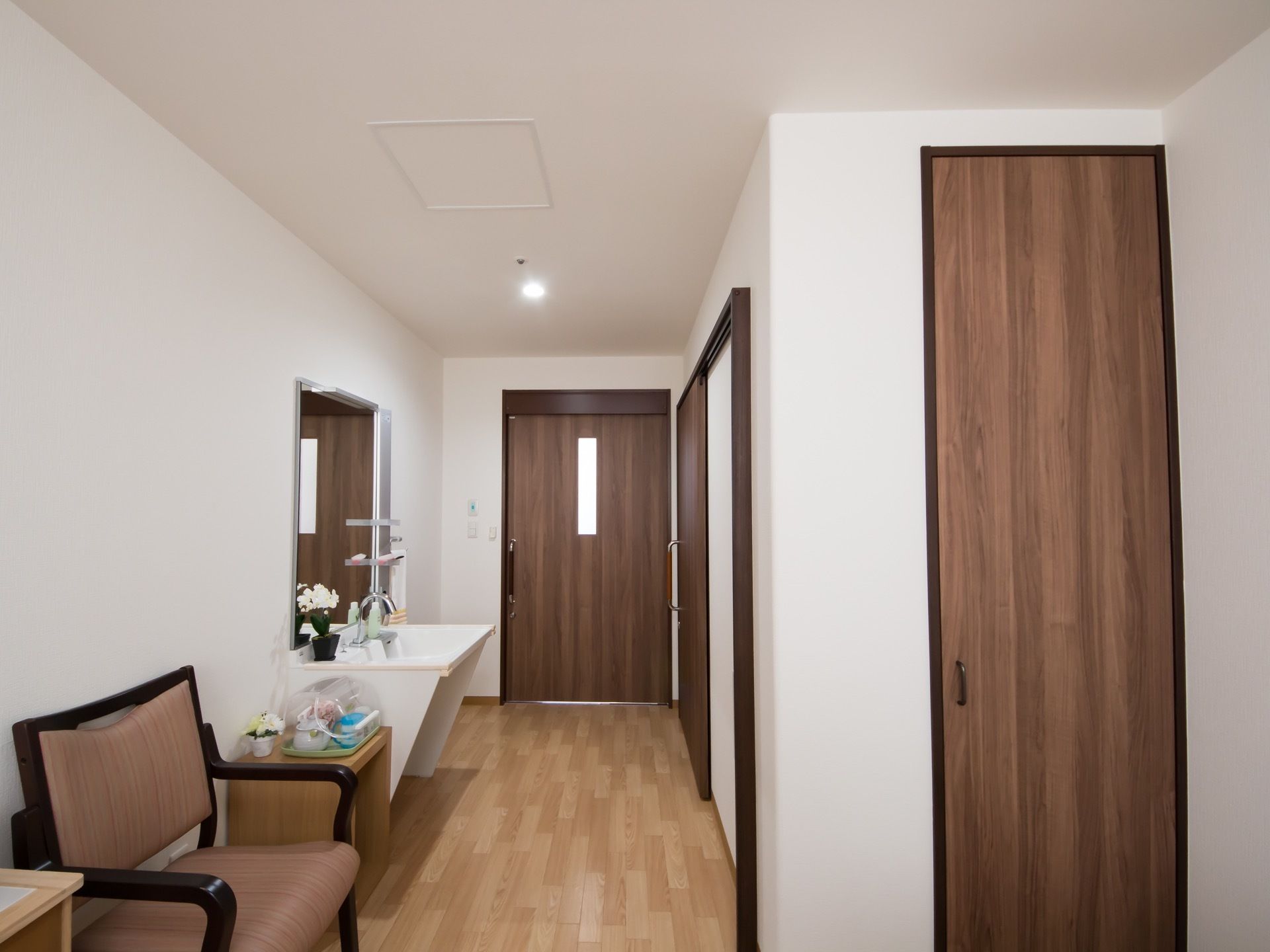落ち着いたブラウン調の建具である。床は木目調のフローリング。出入口あたりに、洗面台が完備されている。