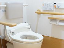 背もたれや手すりが設置された便座にふたはない。壁には操作ボタンがまとめて設置されている。