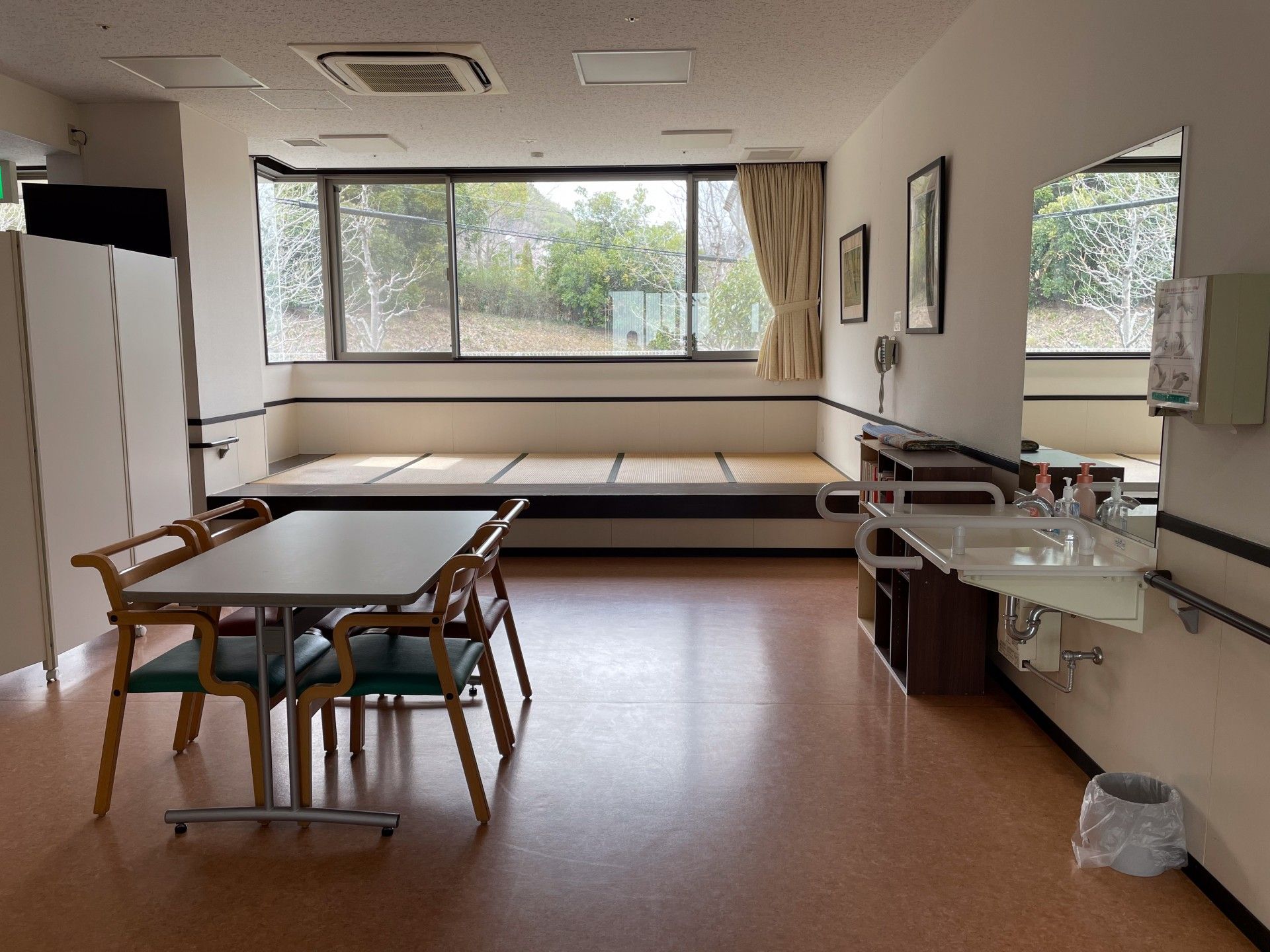 ローテーブルやいすが置かれた部屋にはラグも敷かれ、大きな窓にはカーテンが付いている。