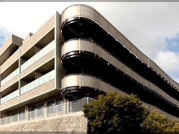 各フロアにベランダが付いた4階建ての建物はベージュ系で重厚感があり、高台に建っている。