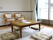 カーテンが付いた大きな窓がある部屋にはローテーブルやいすが置かれ、ラグも敷かれている。