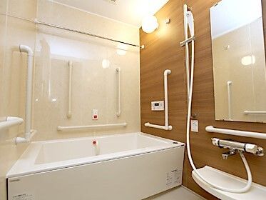 一人用の浴槽が設置された浴室にはたくさんの手すりが設置され、シャワーや鏡、呼び出しボタンもある。