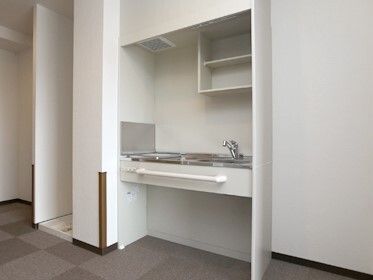足もとにスペースがあるキッチンには手すりも設置されている。フロアはグレーのカーペットが敷かれている。