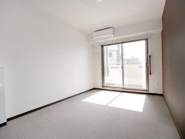 エアコンが付いたシンプルなデザインの部屋には家具や家電は置かれておらず、大きな窓が付いている。