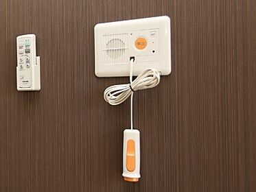 白とオレンジの緊急通報装置が設置されている。白いコードがまとめられ、通話ができるタイプ。