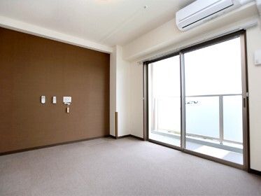 ベランダ付きの部屋は明るく、窓にはカーテンはない。エアコンや緊急通報装置が設置されている。