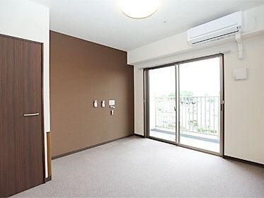 エアコンが付いたシンプルな部屋には家具や家電は置かれておらず、大きな窓の外には周辺の風景が見える。