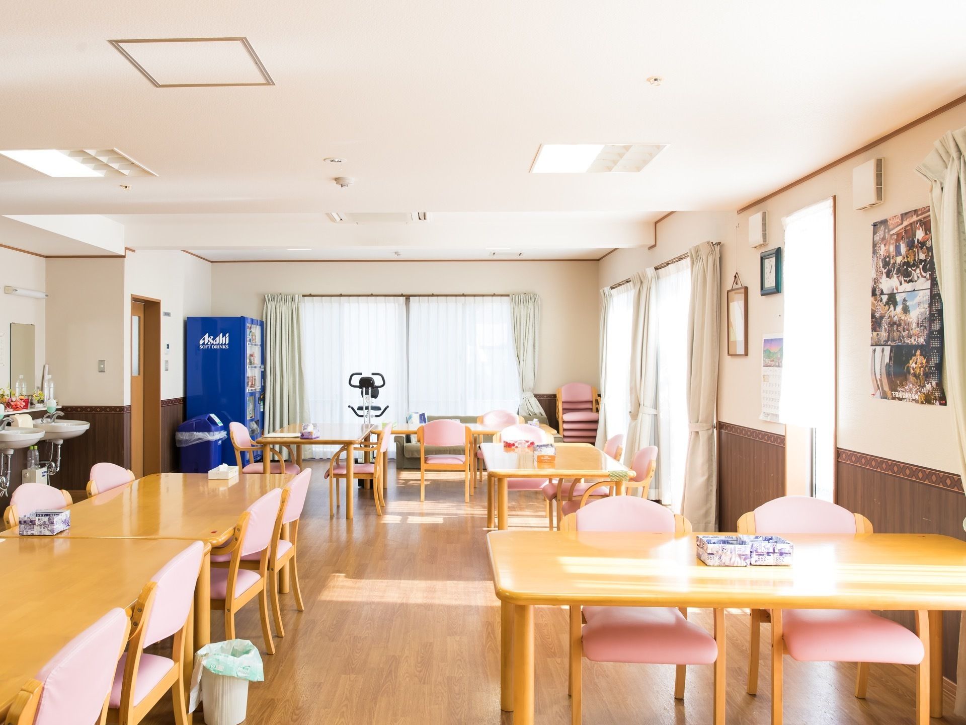 食堂の壁際に洗面台が２つ並んで設置されている。その近くに有名な飲料メーカーの自動販売機が置かれている。