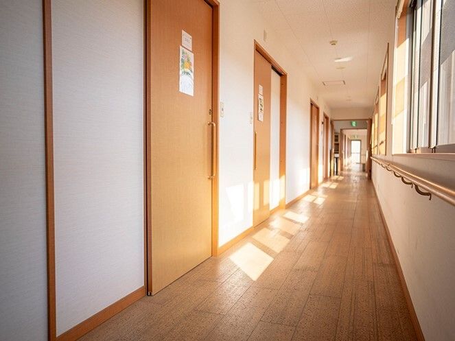 まっすぐな廊下の右側には窓、左側には居室のドアが並び、幅も広く取られている。壁には手すりも付いている。