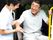 手すりにつかまり車に乗る高齢男性と介助をするヘルパー