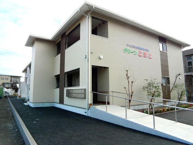 赤や緑、青い文字で住宅名が外壁に書かれた2階建ての建物はアットホームな雰囲気。玄関先には手すり付きのスロープがあり安全に移動できる。