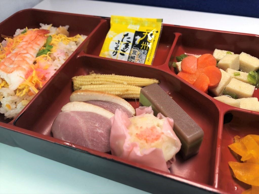 鴨のロースのスライス、茹でたエビや錦糸卵が乗ったちらし寿司、ヤングコーン、煮物、ふりかけなどが仕切られたスペースに詰められた弁当風の食事。