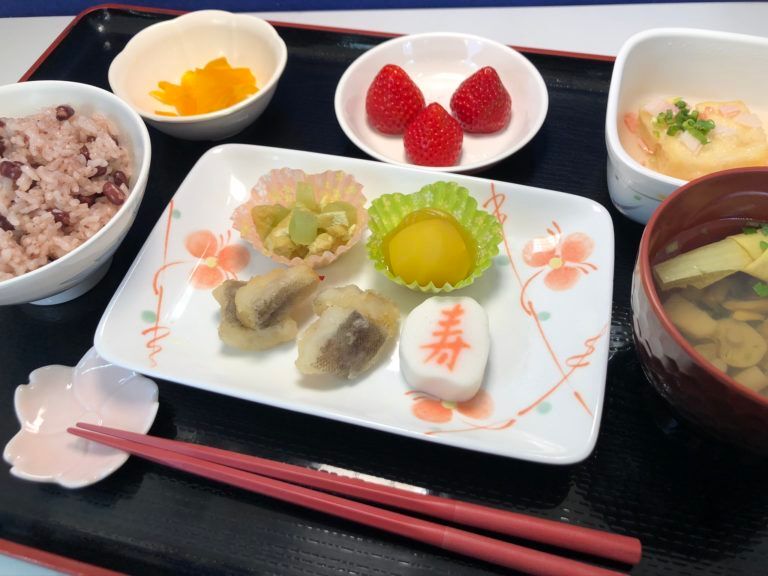 赤飯と吸い物と栗きんとんや竜田揚げ、苺のデザートが付いたメニュー
