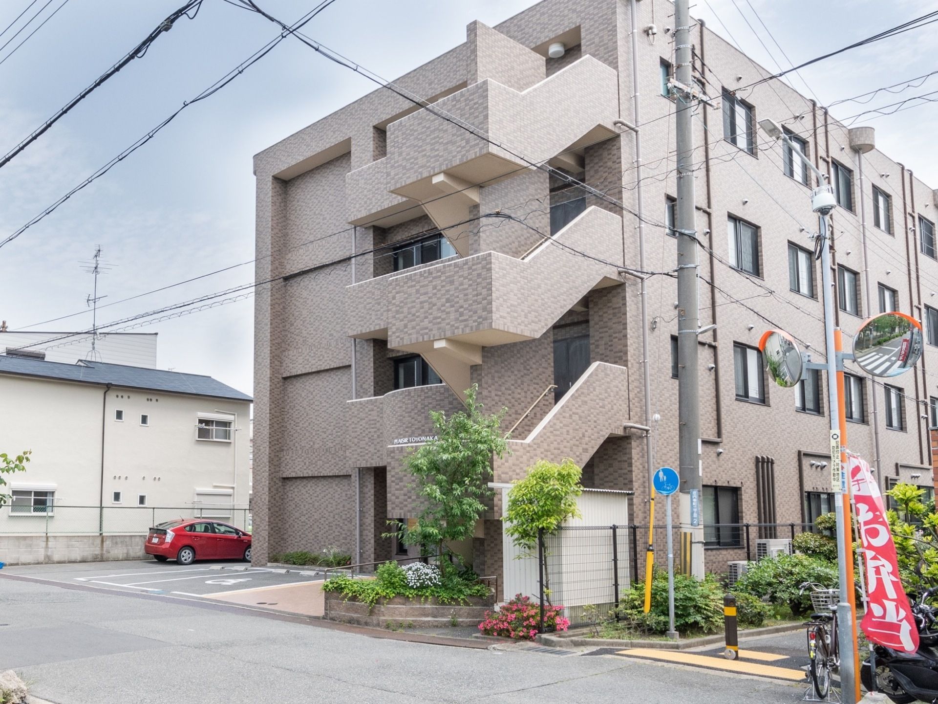 建物は４階建てで外階段からのご来館も可能である。施設前は遊歩道になっている。建物外周に駐車スペースがある。
