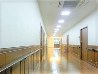 幅の広い廊下は手すりが両サイドにつき、紹介も設置されている。居室のドアが並んでいる。