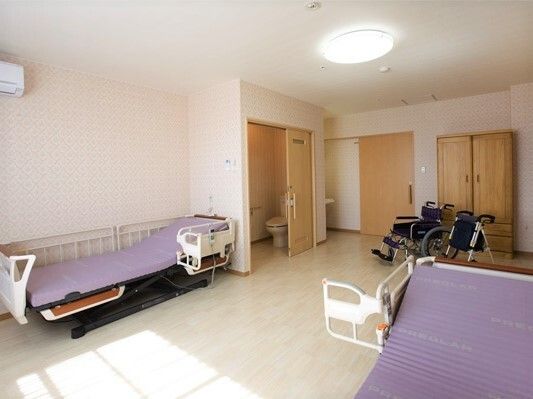 ベッドが二つ置いてある施設内の二人部屋の様子。トイレと収納がある広めの部屋